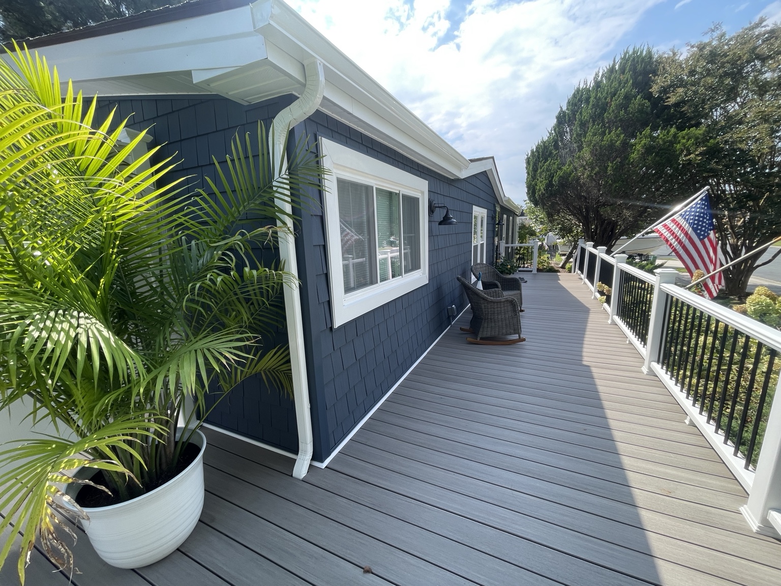 Real Project Pro deck renovation with blue siding, white posts, and black railings